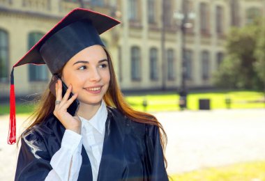 Kadın onun mezuniyet günü. Kullanım akıllı telefon. Üniversite, eğitim, dijital teknoloji, mobil iletişim ve mutlu insanlar - kavram.