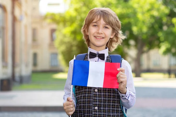 Boy schoolboy with the flag of France on the background of the school. The student of college. Learn French.