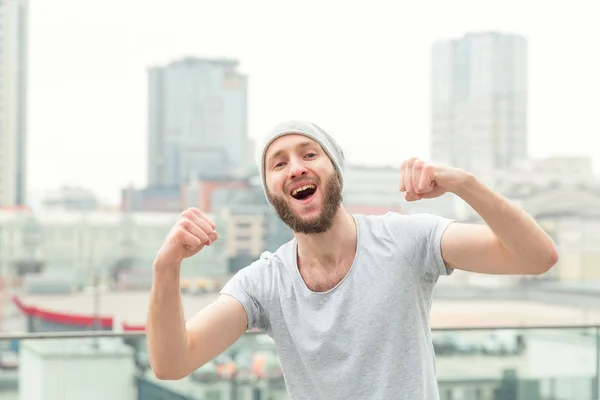 幸せな男は都市の背景の上に立っての喜びから彼の手を引き上げた チャンピオン — ストック写真
