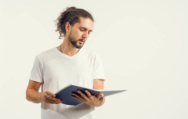 Sakallı genç adam açık bir kitap ya da defter okuyor. Metin için yer, reklam dersleri için konsept.