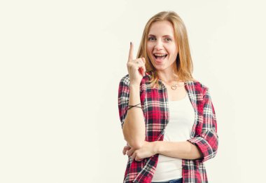Harika fikir! Güzel mutlu genç kadın hafif bir arka plan karşı dururken parmak yukarı işaret.