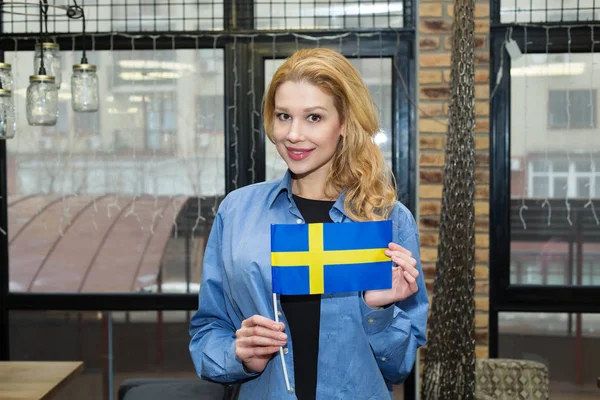 美丽的女性金发女郎与瑞典国旗在办公室 旅行和教育 学习瑞典语 — 图库照片