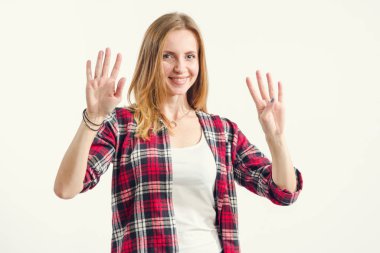 Güzel genç kadın hafif bir arka plan üzerinde dururken dokuz parmak gösterir. Sayı 9 - kavram.