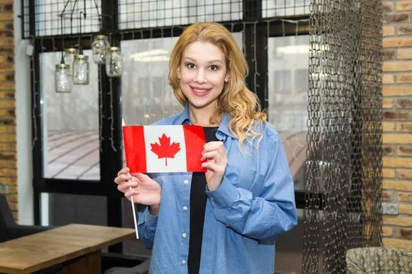 Beautiful blond woman with the flag of Canada. Study abroad, travel.