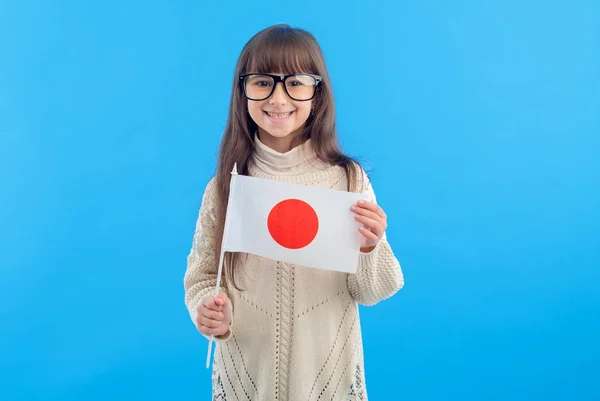 青い背景に日本の国旗を持つ眼鏡をかけた小さな女の子 海外教育 日本語を学ぶ — ストック写真
