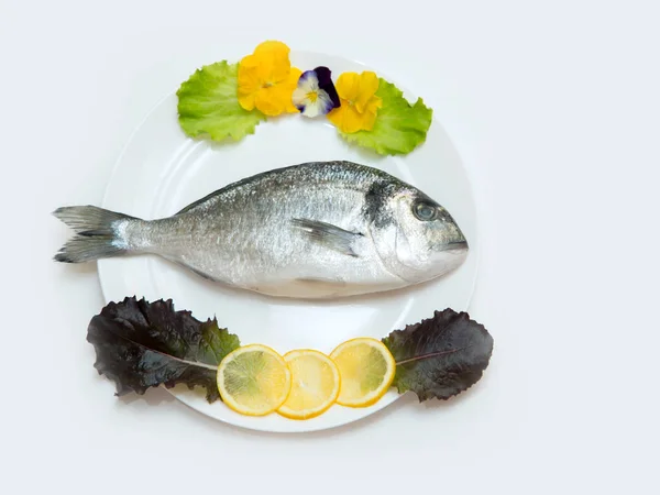 One raw fresh dorado fish in a plate is decorated before cooking