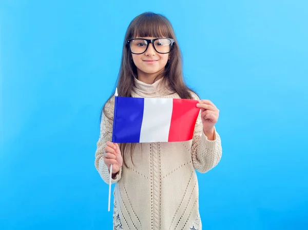 青い背景に立つフランスの旗を持つ小さな女の子 留学中の女子学生 — ストック写真