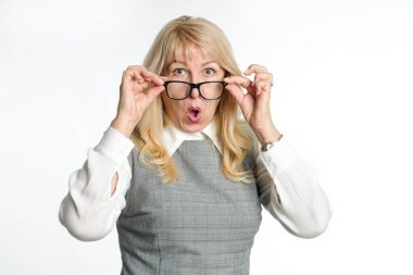 Gözlük şaşırttı olgun kadın hafif bir arka plan üzerinde duygularını jestleri.