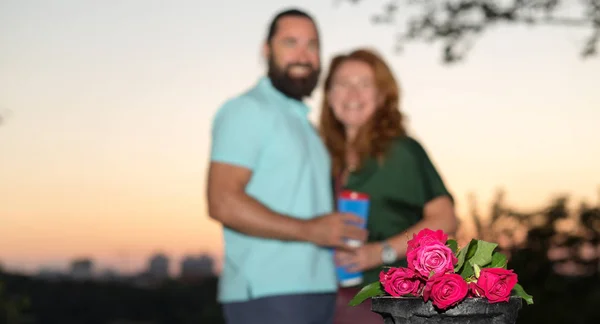 バラの花束 背景に恋にぼやけた中年の成熟したカップル 公園の夕方の日付 夏の散歩 男女一緒に 花を贈る — ストック写真