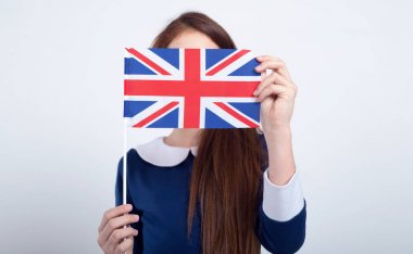 Kızıl saçlı kız gri bir arka plan üzerinde duran Büyük Britanya bayrağı ile yüzünü örttü. Schoolgirl, yurtdışında eğitim.