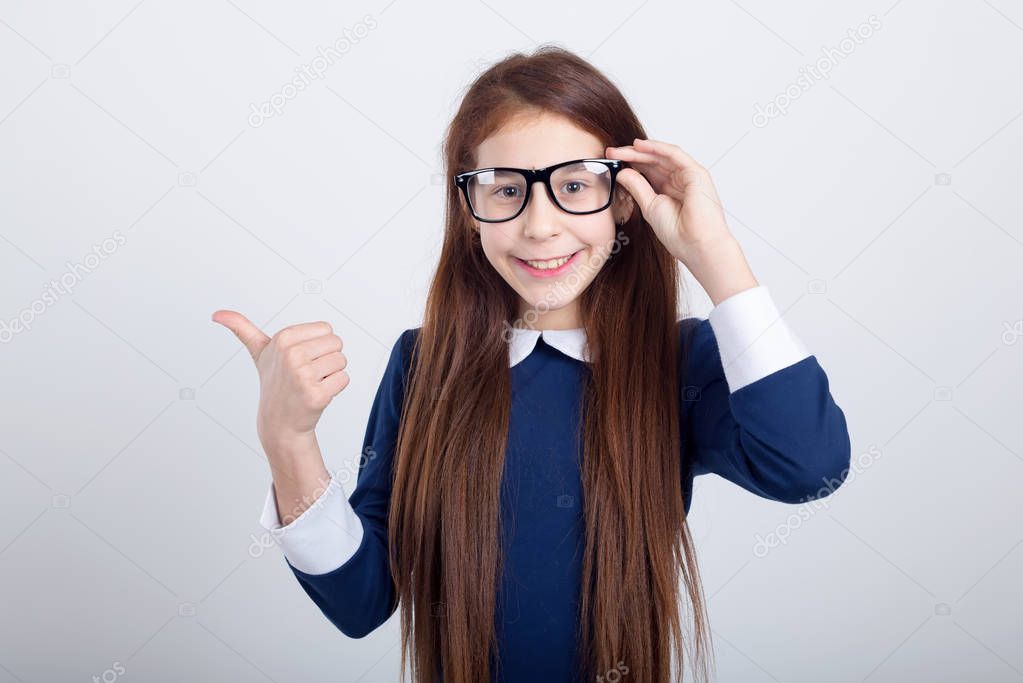 Portrait of a pretty school girl in glasses pointing finger away.