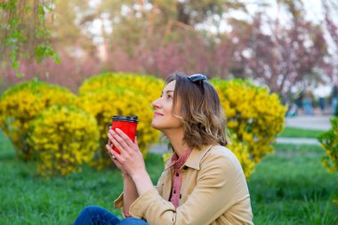 Parkta bir fincan kahve ile mutlu genç kadın.