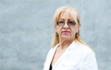 Gözlüklü olgun bir kadının yakın çekim portresi.