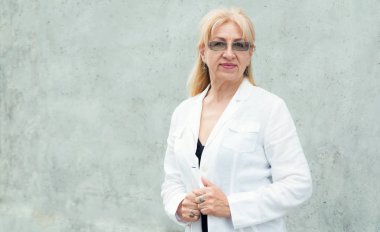 Gri bir duvar arka plan karşı olgun bir iş kadını Portresi.