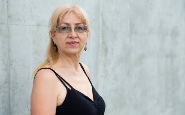 Gri arka planda mutlu yaşlı kadın.