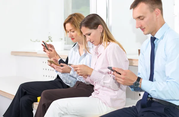 Skupina Podnikatelských Lidí Dívá Telefonů Když Sedí Kanceláři — Stock fotografie