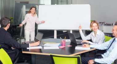 İş kadını ofiste bir sunum yapıyor. Müdür çalışanlarla konuşur. Yeni projenin planına söyleyin.