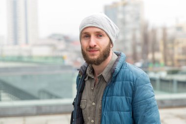 Şehrin arka planında ceketve şapkalı genç bir adamın portresi.