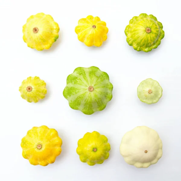 Squash vegetable. Group of green and yellow pattypan squashes, on white table background. Square image.