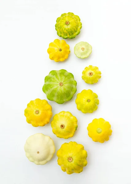 Top view multicolor squash vegetable. Group of green and yellow pattypan squashes, on white table background.