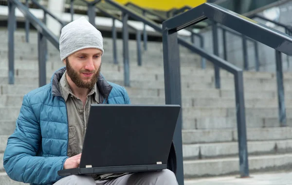 男性自由职业者使用笔记本电脑做远程工作 胡子男子在笔记本电脑上工作 而坐在户外的台阶上在城市 — 图库照片