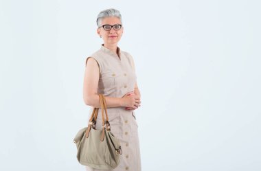 Açık mavi bir arka plan üzerinde elinde bir çanta ile gözlük güzel olgun kadın. Anne, gri saçlı kadın orta yaş.