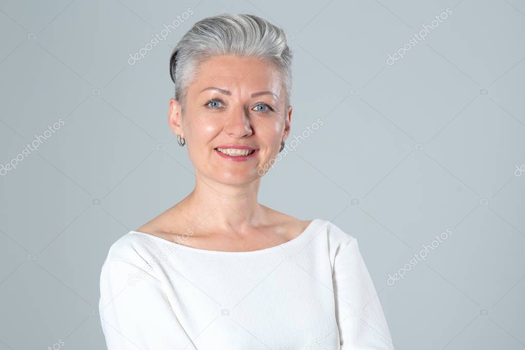 Portrait of a middle aged woman on a gray background.