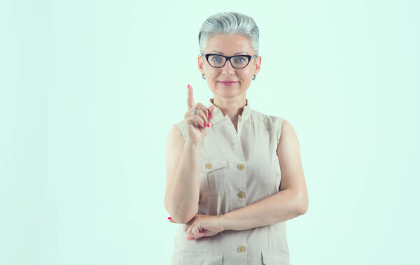 Attention! Portrait of a female teacher with glasses on a light blue background. Beautiful mature woman. Middle age.