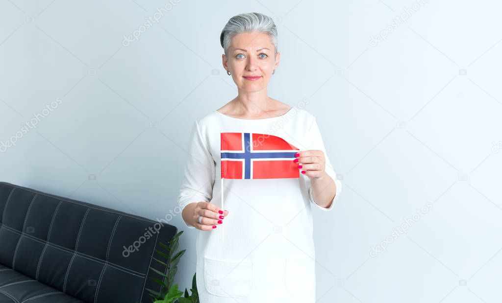 Portrait mature Scandinavian woman holding a flag of Norway.