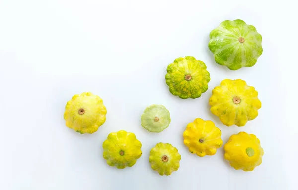 Pattypan squashes vegetable. Group of green and yellow pattypan squashes, on white table background.