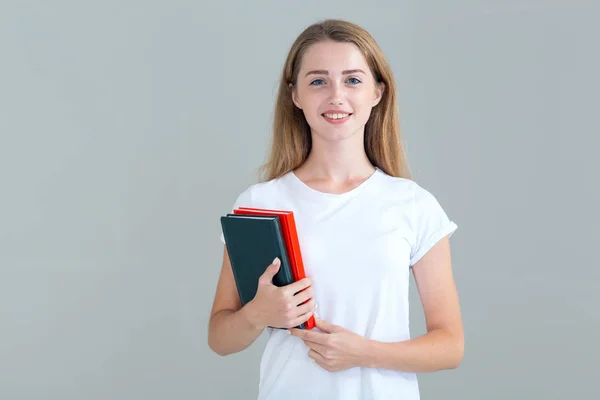 年轻的女学生手里拿着书 手里拿着课本 被隔离在灰色背景上 教育理念 — 图库照片