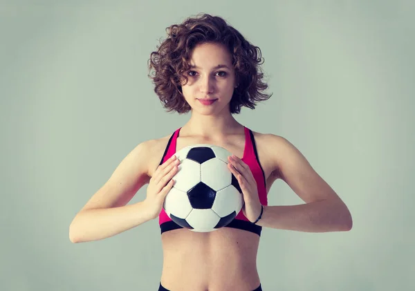 灰色の背景に立つサッカーボールの若い美しい女性の肖像画 — ストック写真