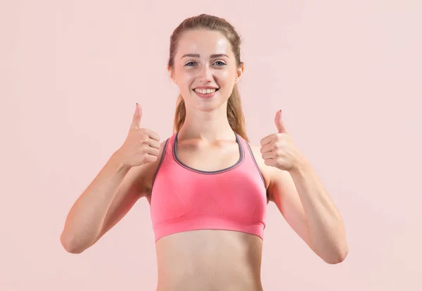 Ung Fitness Kvinna Visar Tummen Upp Stående Ljusrosa Bakgrund — Stockfoto