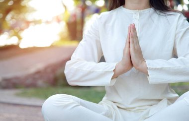 Namaste'de kadın ellerini kapatın. Tapınağın ve doğanın arka planı üzerine meditasyon. Bir inziva merkezinde Yoga dersleri.