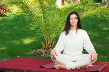 Esmer kadın doğa arka plan üzerinde meditasyon. Geri çekilme yoga egzersizleri.