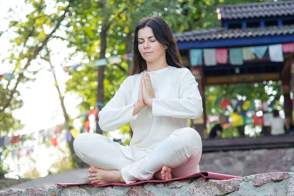 Brunette woman meditates on nature background. Yoga exercises in retreat.