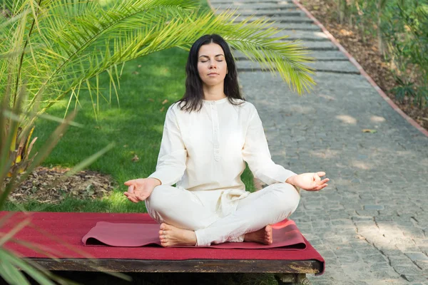 Brunette woman meditates on nature background. Yoga exercises in retreat.