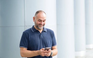 Elinde telefon olan mutlu orta yaşlı bir adam bir sosyal ağ için bir mesaj yazar ve okur. Online.