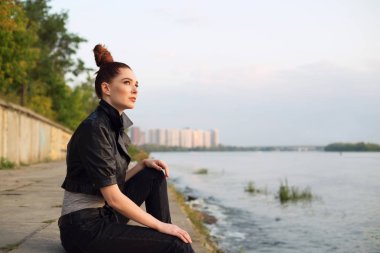 Gün batımında şehrin ve nehrin arka planında güzel bir kadının portresi..