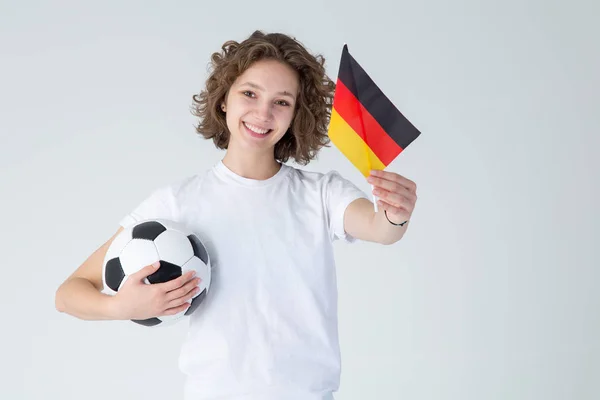 一个年轻美丽的女人 有一个足球和德国国旗在一个轻的背景 足球迷 — 图库照片