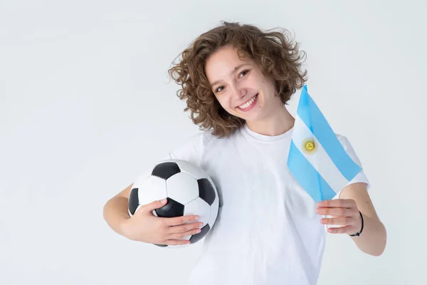 一个年轻漂亮的女人 有一个足球和阿根廷国旗在一个轻的背景 足球迷 — 图库照片
