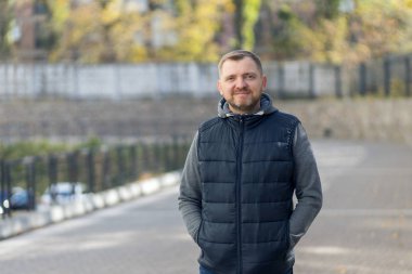Bir şehrin arka planında sakallı orta yaşlı bir adamın portresi..