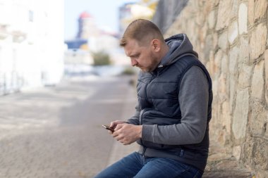 Akıllı telefonlu ciddi orta yaşlı bir adam, sosyal ağlara bir mesaj ya da yorumlar yazıyor..