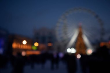 Fuar alanının bulanık görüntüsü. Noel ağacı ve Bokeh 'deki dönme dolap koyu mavi arka planda..