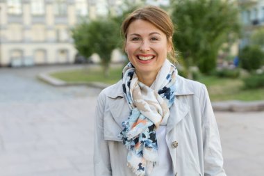 Şehrin arka planında gülümseyen mutlu yetişkin bir kadının portresi..