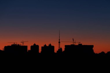 Gün batımının veya şafağın arkaplanına karşı şehir bilgisinin siluetleri. Yatay resim.