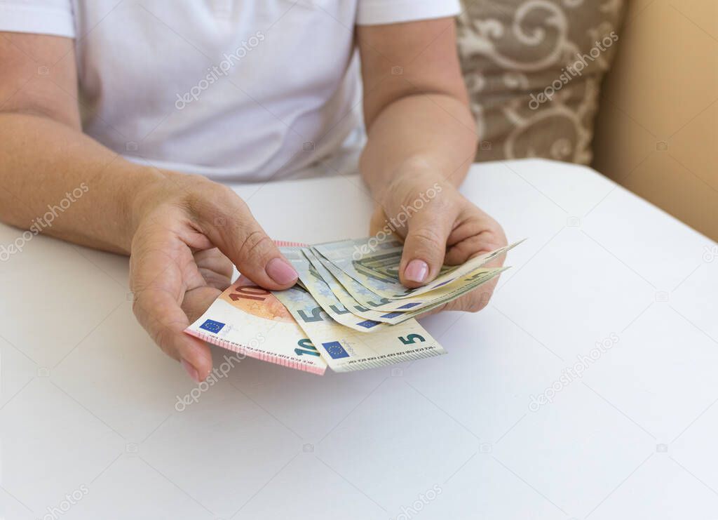 Close-up female hands consider euro money sitting at the table. Paper notes of the European Union of various cost.