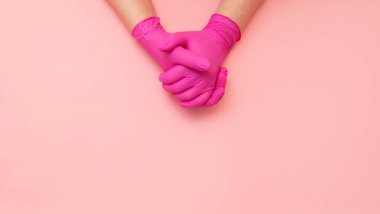 Hijyenik pembe eldivenlerle birbirine kenetlenmiş iki eli kapat. Metin için yer.