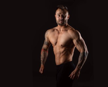 Gülümseyen güçlü adam. Siyah arkaplanda vücut geliştirici.