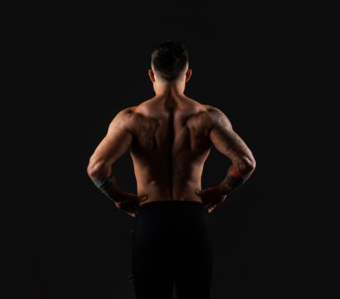 Güçlü adam arkasını görüyor. Siyah arkaplanda vücut geliştirici.